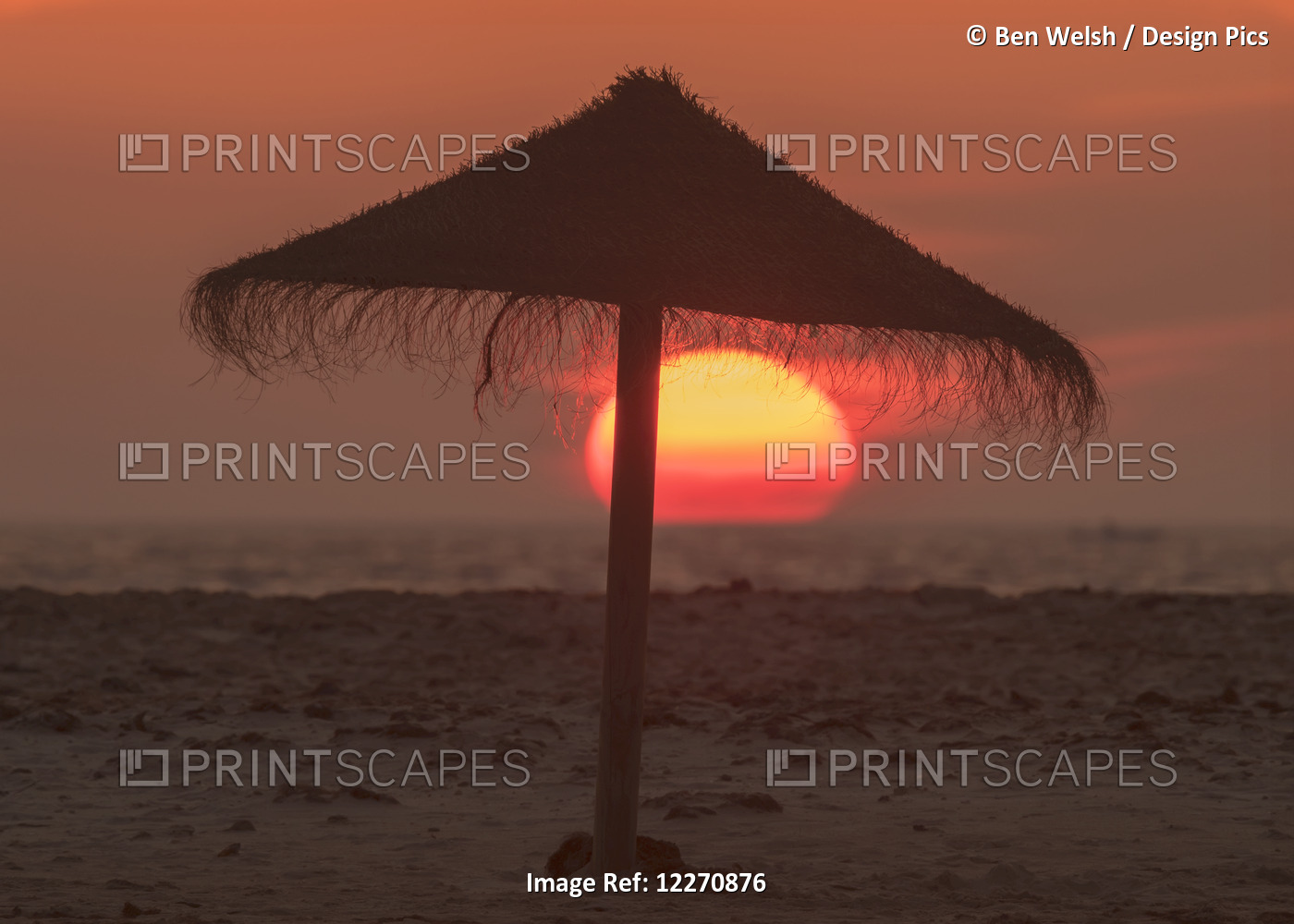 Silhouette Of A Beach Umbrella On The Beach With A Colourful Sun Sinking Into ...