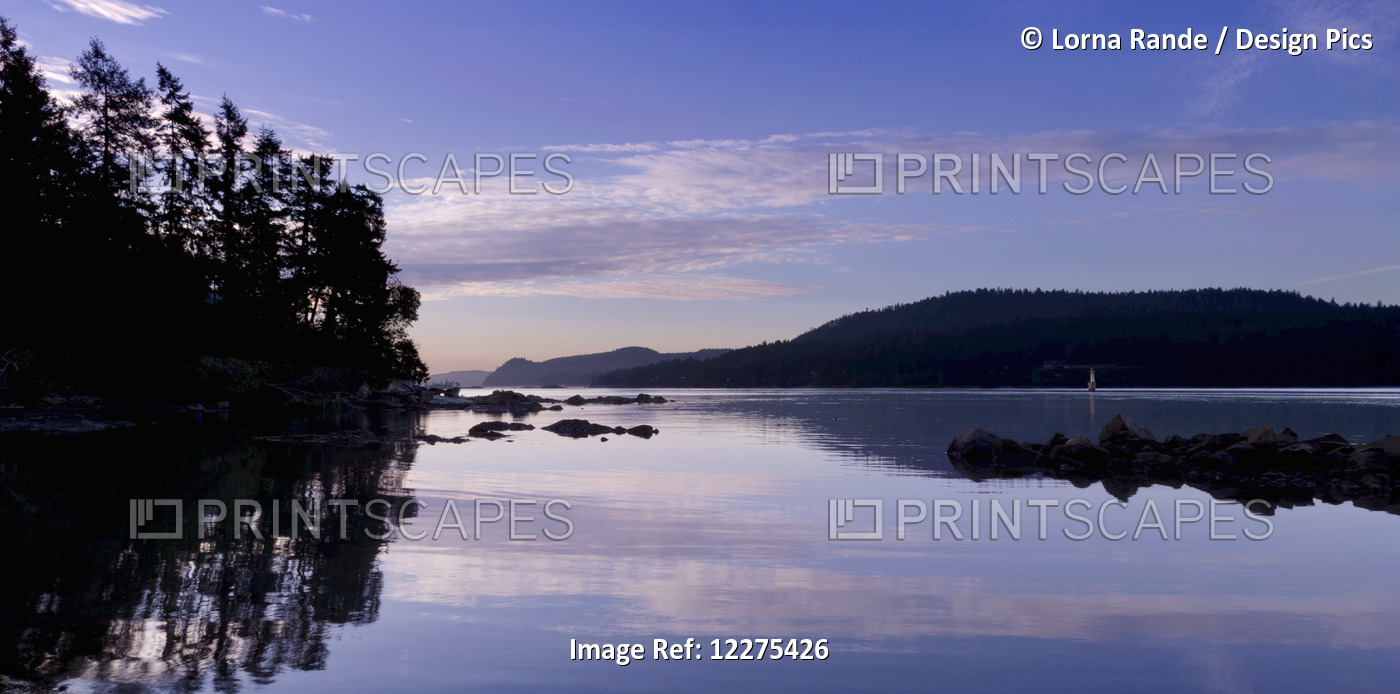 Coastline Reflected In The Water At Sunset With Silhouette Of Trees At The ...