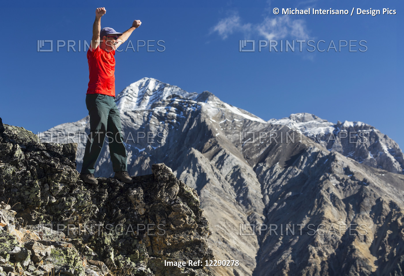 Male Hiker Standing With Arms Raised In The Air On Top Of Mountain Ridge ...