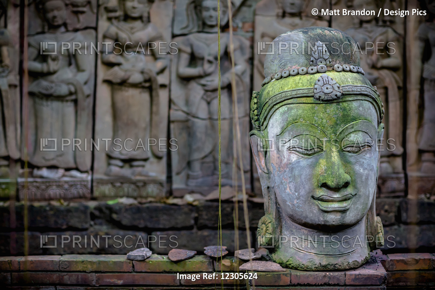 A Terra Cotta Head Of Buddha Sits In Front Of Bas-Relief In A Terra Cotta ...