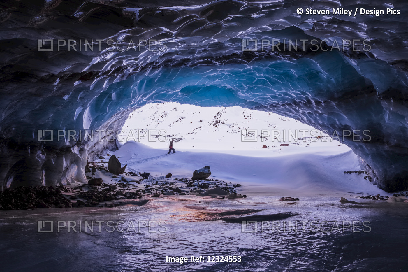A Man Is Framed By The Entrance To A Large Ice Cave Near The Terminus Of ...