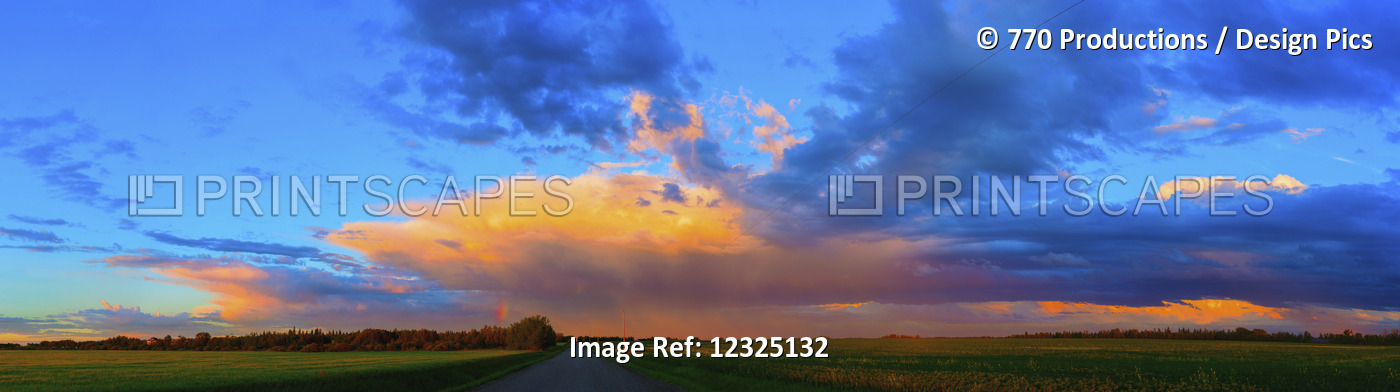 Glowing Golden Clouds Over Green Fields And A Country Road At Sunset; Alberta, ...