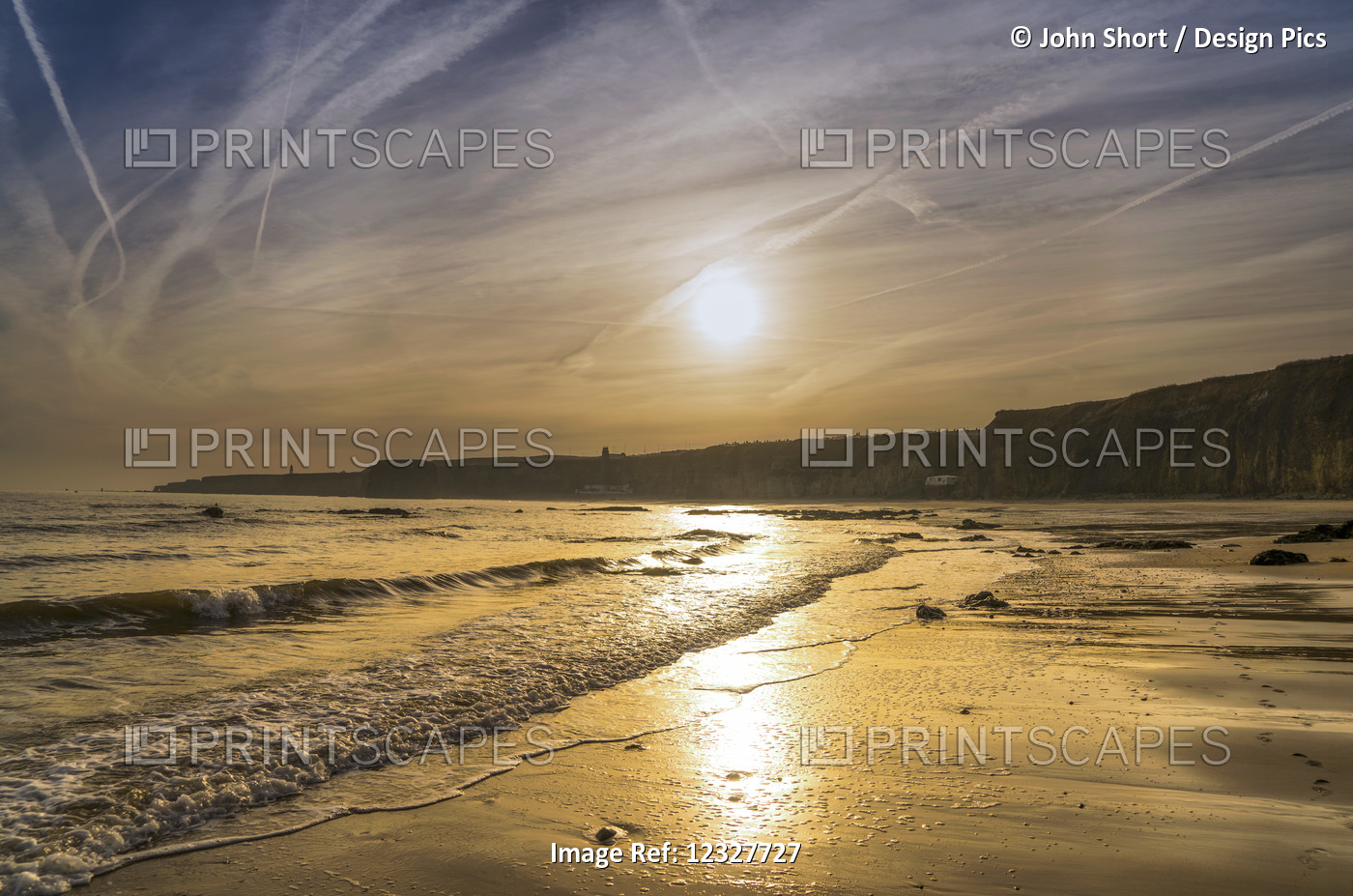 A Sinking Sun Glows In The Sky And Reflects Off The Wet Sand Along The Coast; ...