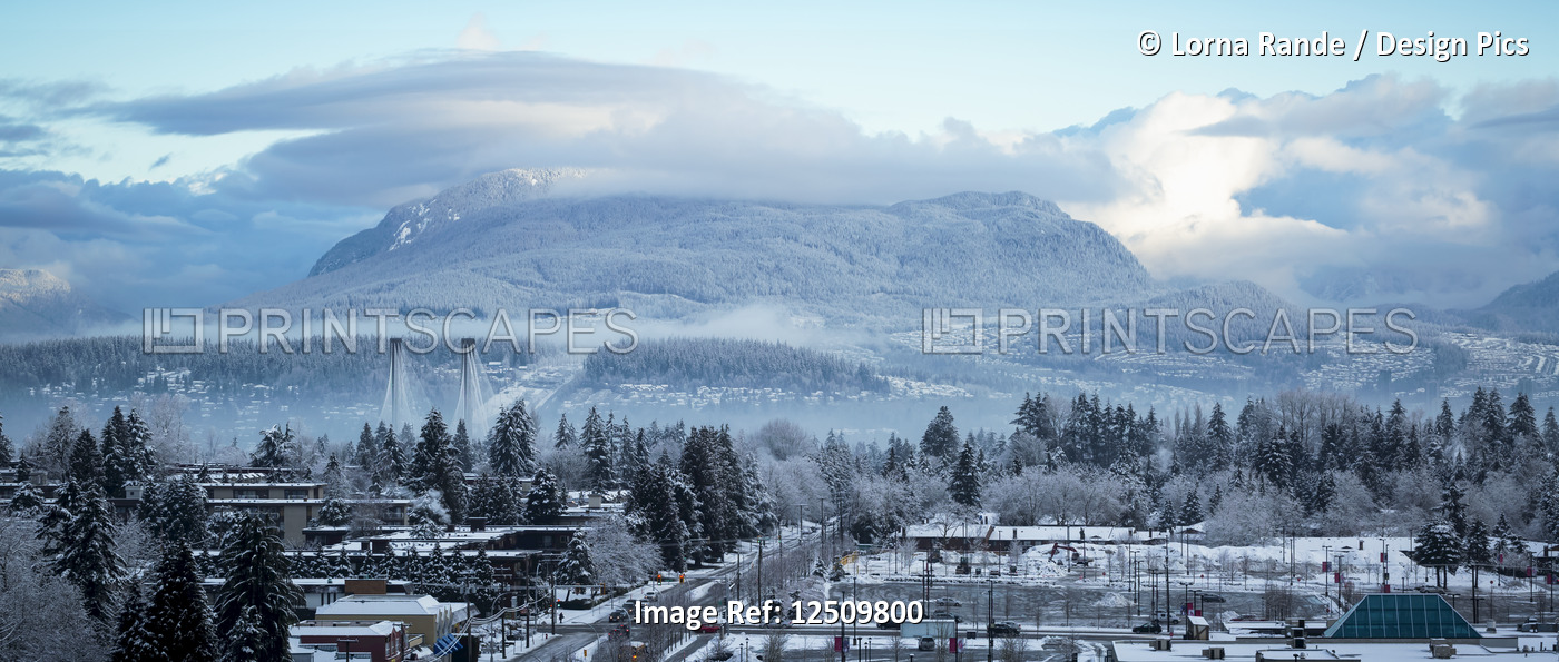 View of clouds hovering over mountains and snow covering the neighbourhood in ...