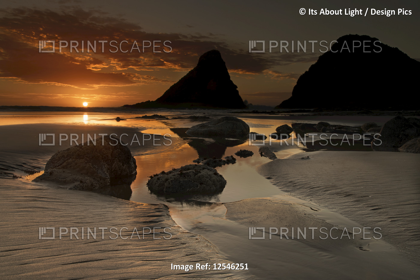 Sunset along the Oregon coast with silhouetted rock formations and a golden sun ...