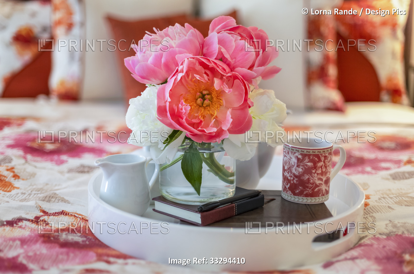 Bouquet of pink and white peonies on a bed tray with a coffee mug, journal and ...