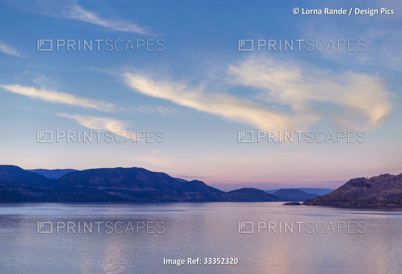 Okanagan Lake at sunset with the silhouetted Coast range mountains along the ...