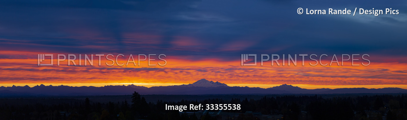 Panoramic view of a glowing sunset sky over a silhouetted mountain range; ...