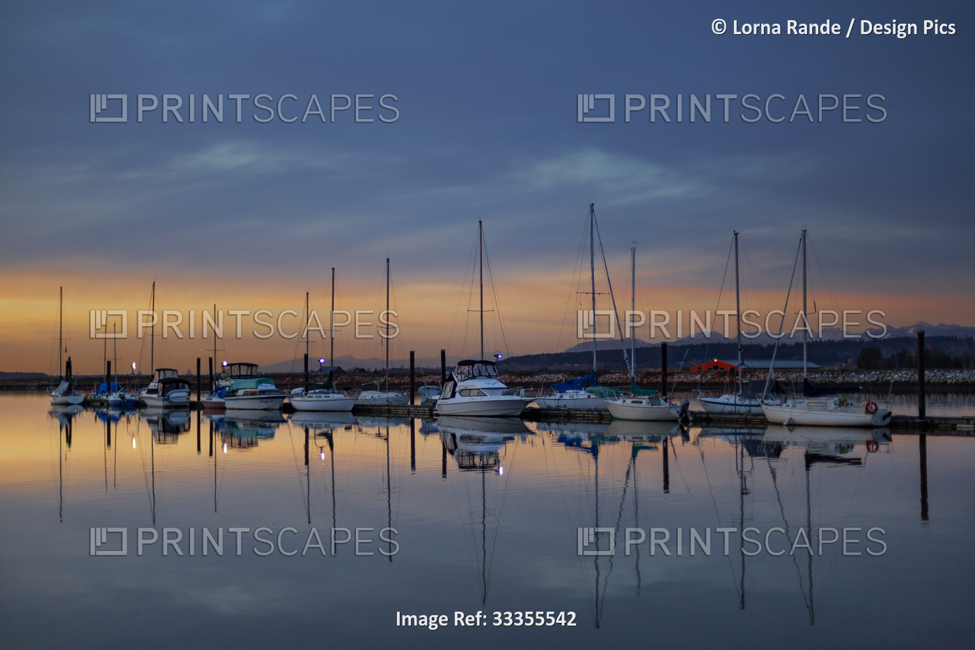 Sailboats mooring in a marina at sunset at Crescent Beach with a mirror image ...