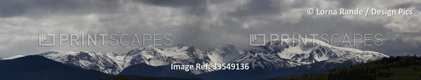 Black and white image of the rugged and snowy mountain range under a cloudy sky ...