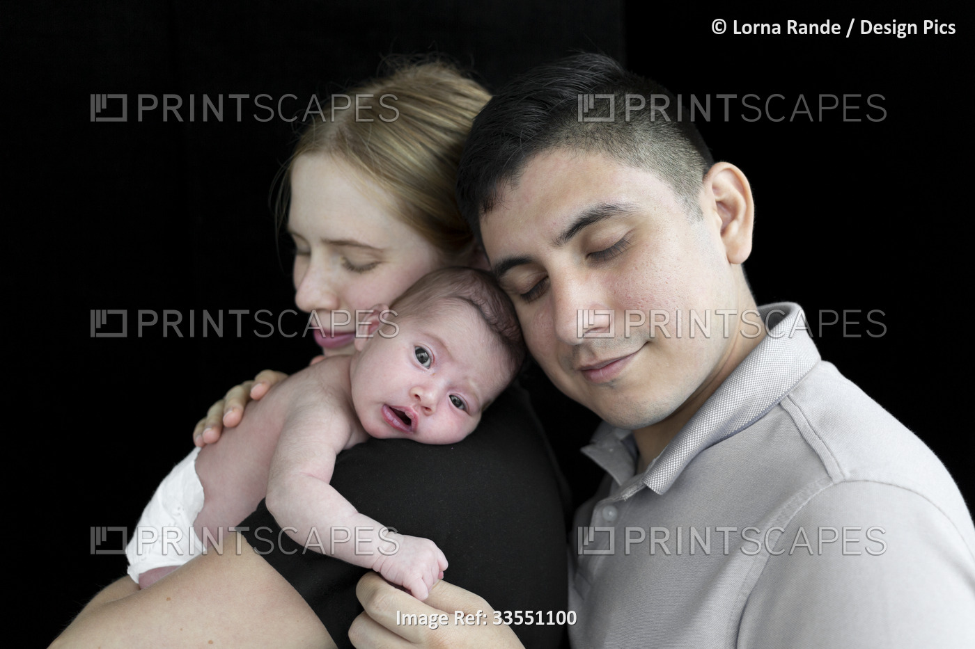 Family portrait of a young couple with a newborn baby girl against a black ...