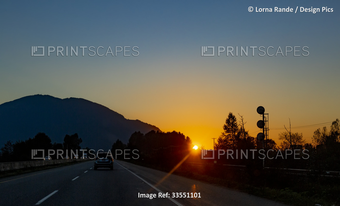 Car driving down the highway with sunset light; Chilliwack, British Columbia, ...