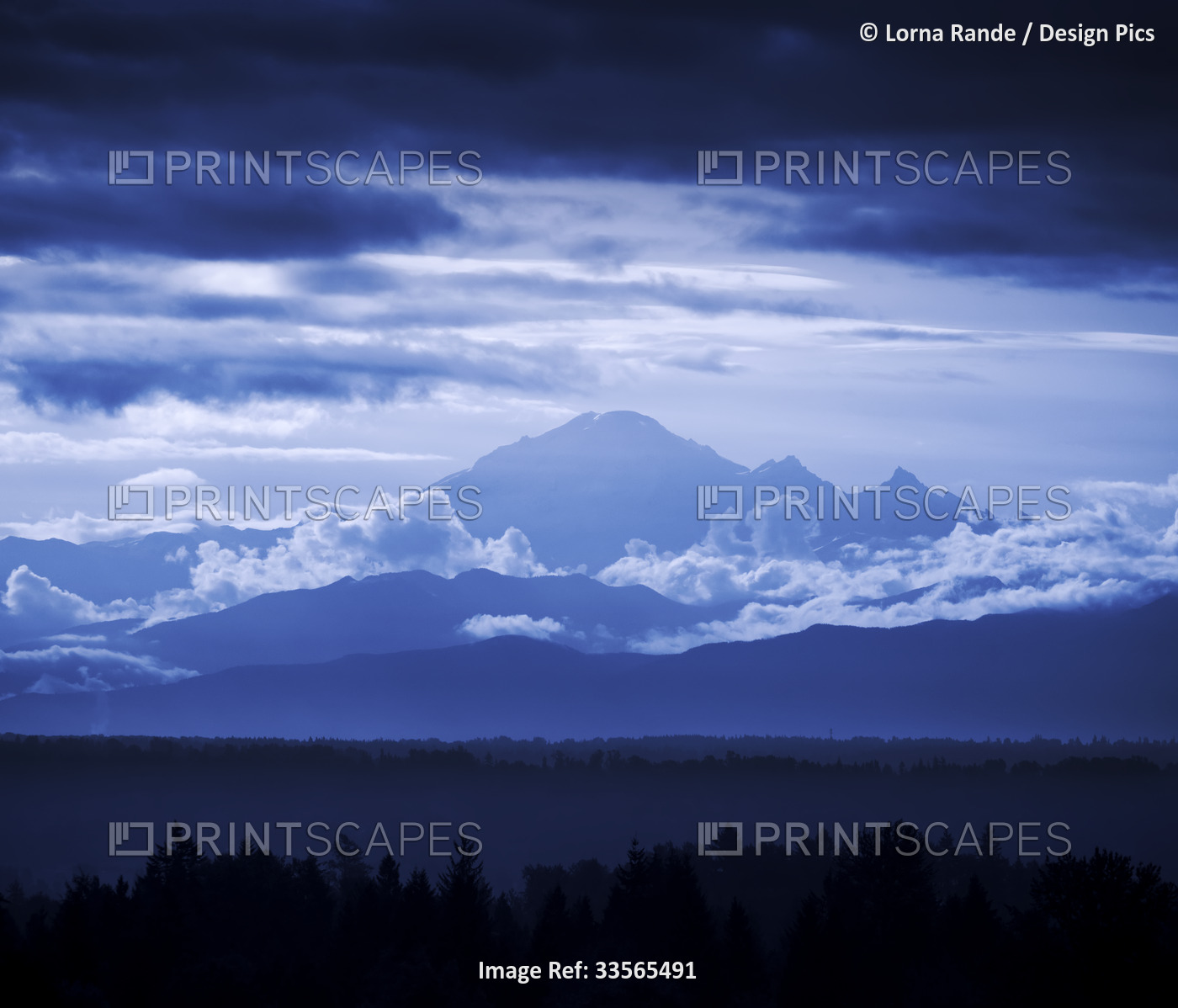 Peaks of Mount Baker with clouds and silhouetted forests in the valley; Surrey, ...