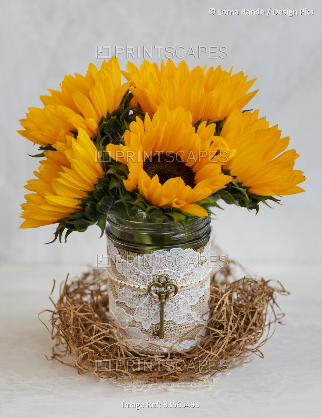 Sunflower bouquet in a decorative jar with lace, pearls and a vintage key; ...
