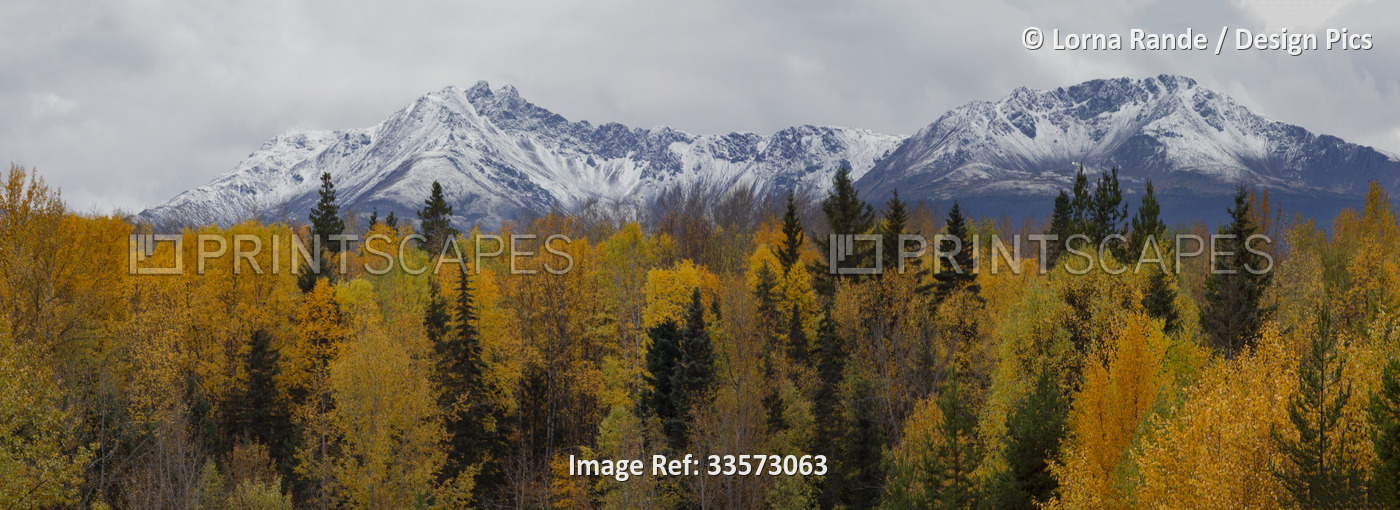 Vast and dramatic landscape of rugged mountain peaks under a cloudy sky and an ...