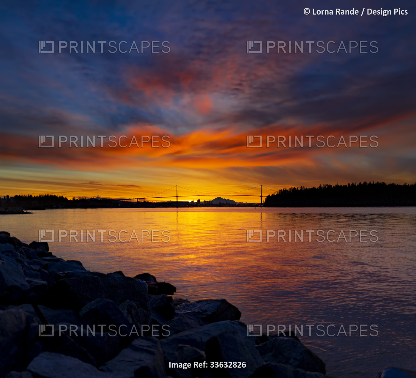 Brilliant colours of a sunrise viewed from the seawall in West Vancouver, with ...
