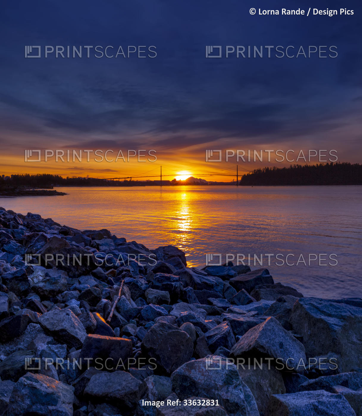 Brilliant colours of a sunrise viewed from the seawall in West Vancouver, with ...