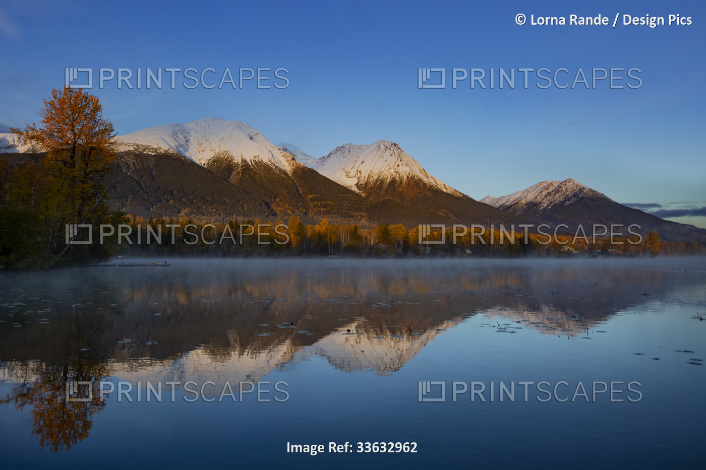 Tranquil Lake Kathlyn surrounded by autumn coloured trees and snow-capped Coast ...