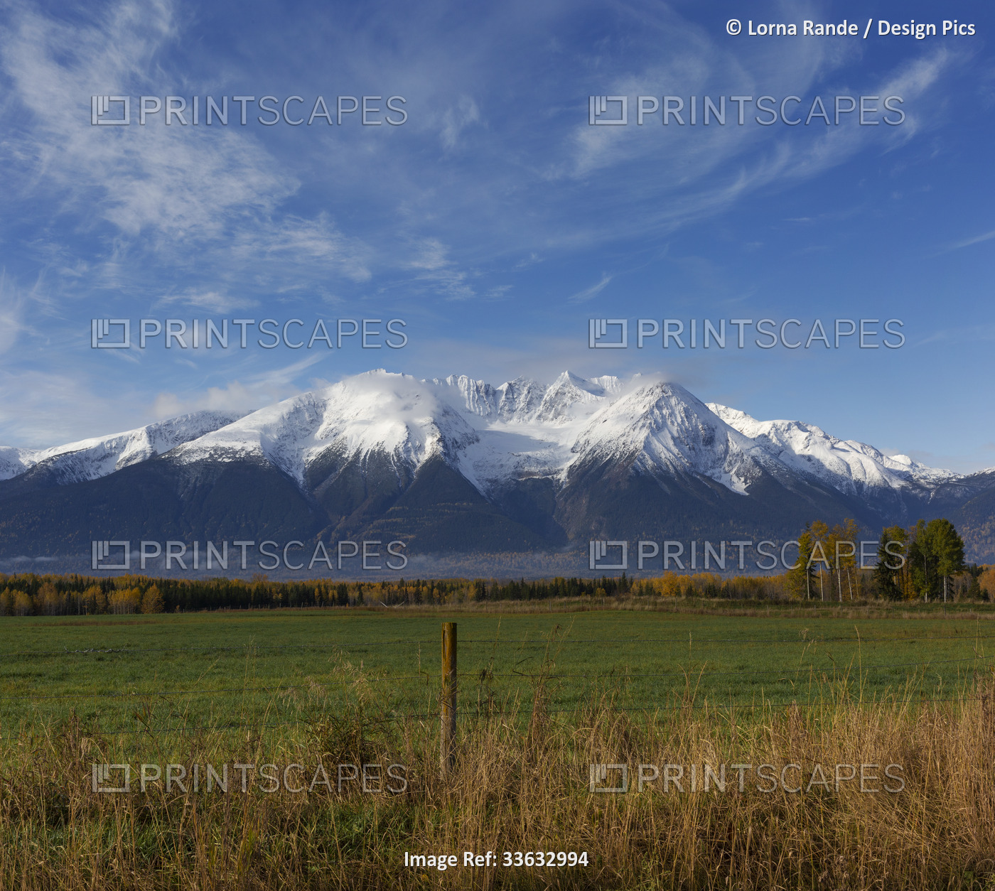 Rugged peaks of a snow-capped Cascade mountain range viewed from a country road ...