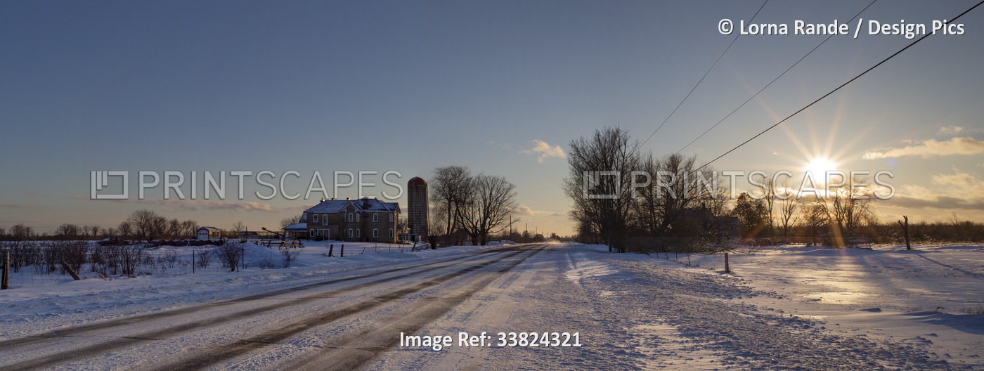Countryside on a winter evening with the glowing sun setting over the ...