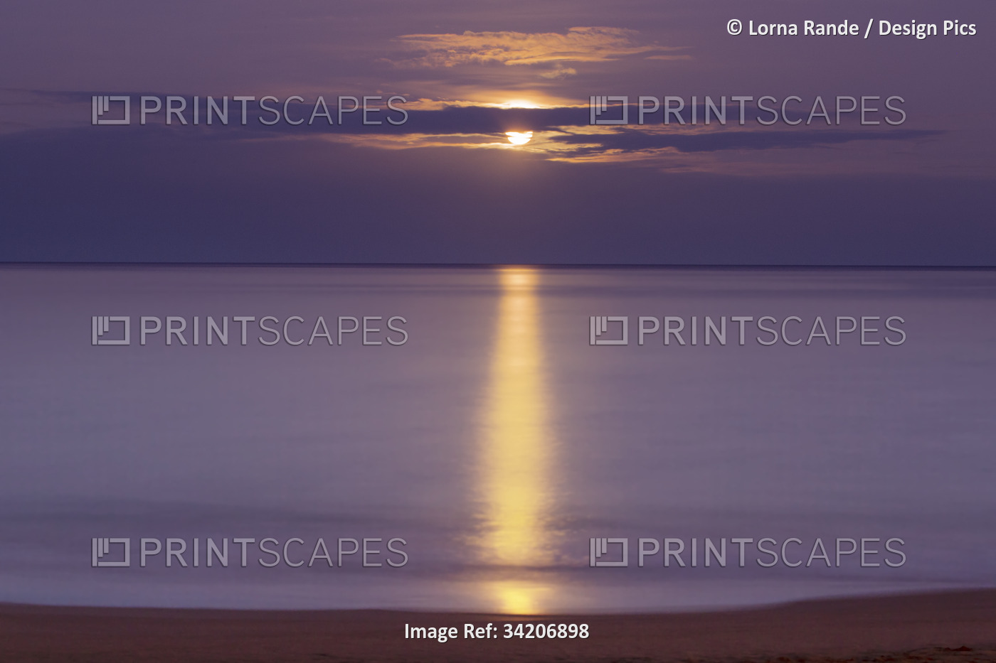 Golden light reflected on the Pacific Ocean with the full moon setting at ...