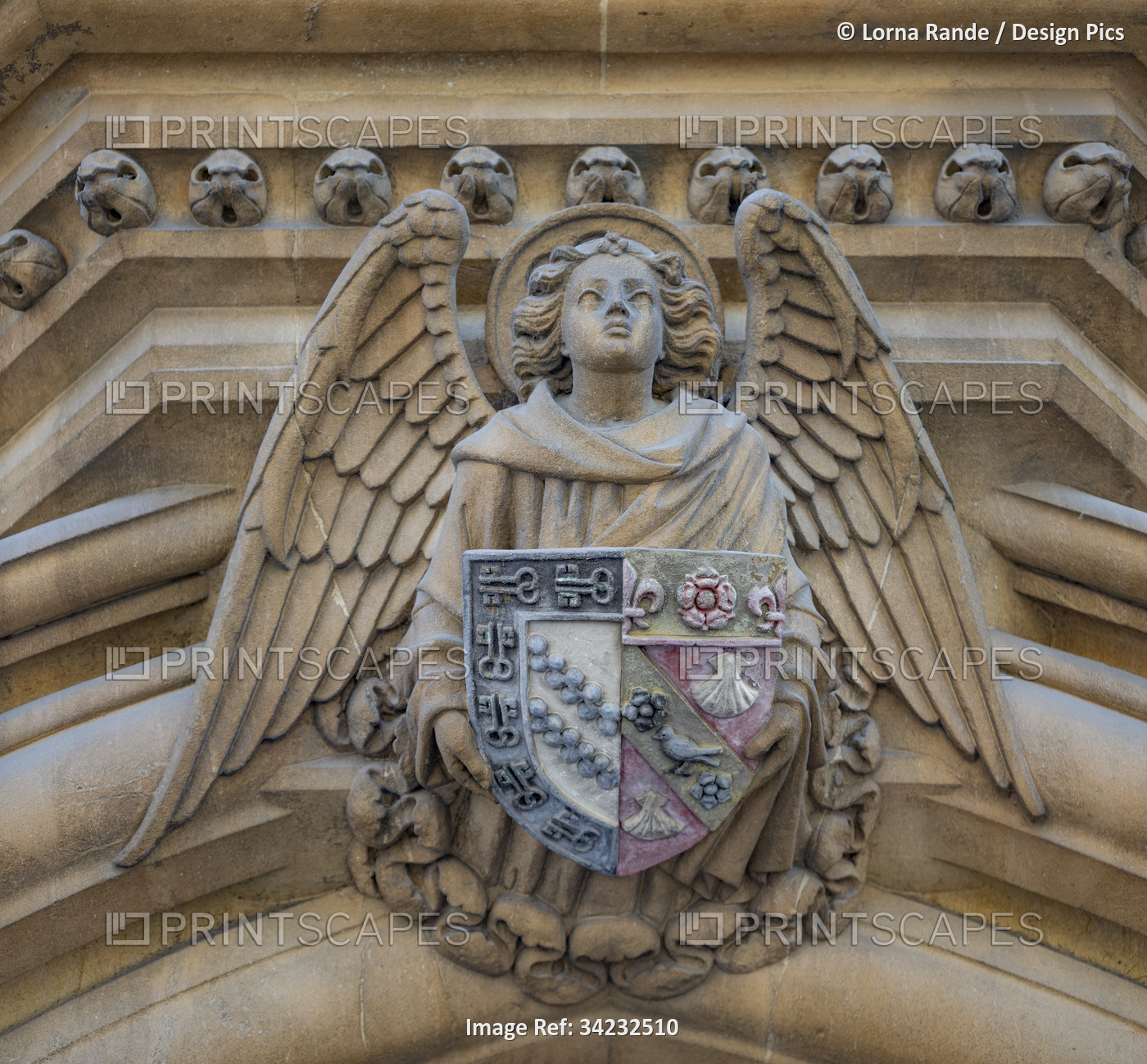 Low angle view of a angel sculpture holding crest on a building; United Kingdom
