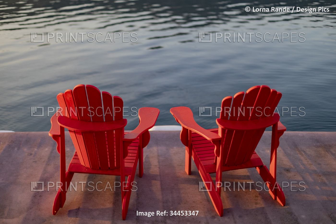 Two red Adirondack chairs on a dock on Sproat Lake at sunset, Vancouver Island, ...