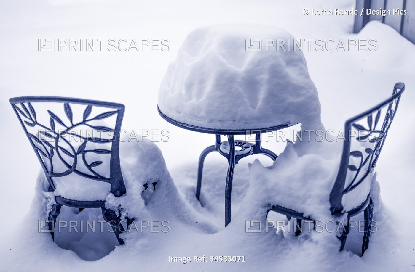 Deep snow covers a patio bistro table and chairs; Surrey, British Columbia, ...